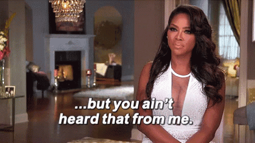 a woman in a white dress is standing in a living room and saying but you ain 't heard that from me .