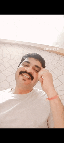 a man with a mustache is smiling and making a funny face .