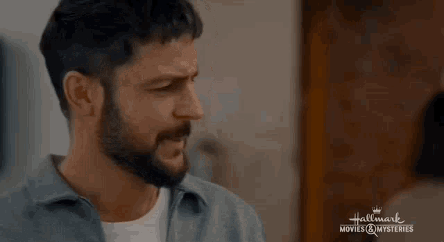 a man with a beard is wearing a gray jacket and a white shirt .