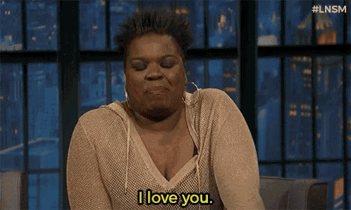 a woman is saying i love you while sitting in front of a window .