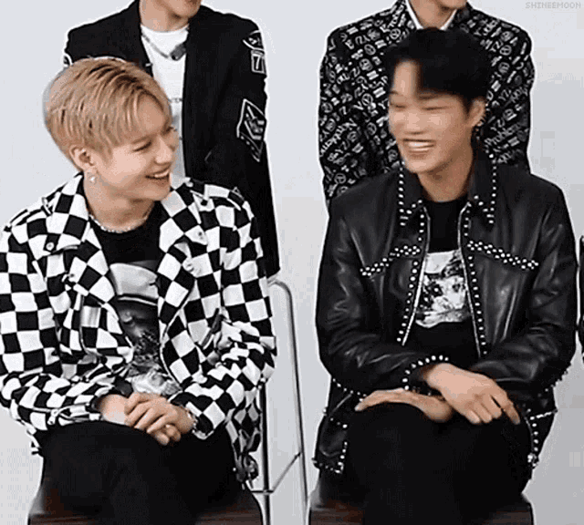 a group of young men are sitting next to each other on a chair and laughing .