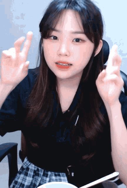 a girl in a black shirt and plaid skirt is making a peace sign