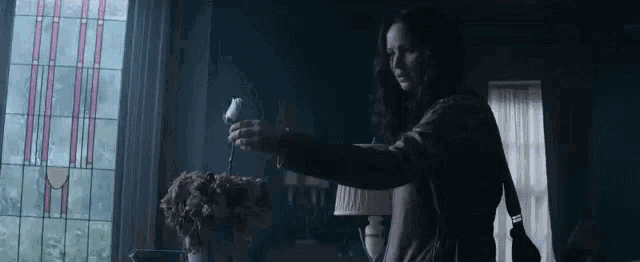 a woman in a leather jacket is holding a white bird in a dark room .