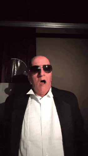 a bald man wearing sunglasses and a tuxedo