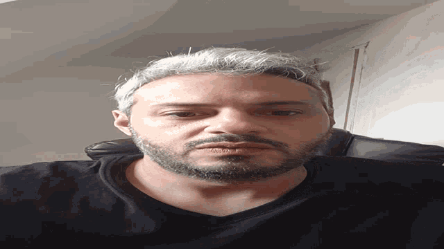 a man with a beard wearing a black shirt looks down at the camera