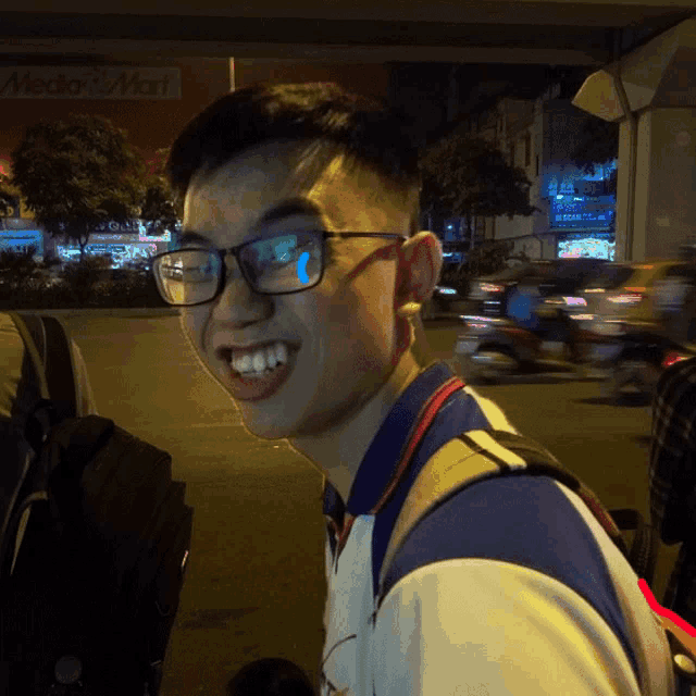 a young man wearing glasses is smiling in front of a sign that says mado mart