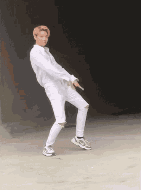 a man with pink hair and white pants is dancing