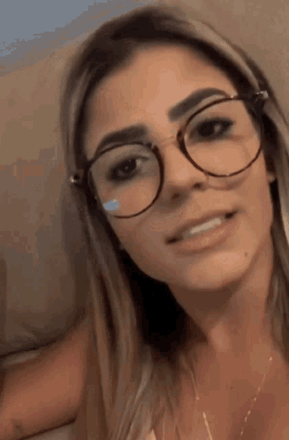 a woman wearing glasses and a necklace is smiling