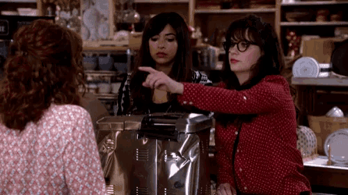 a woman in a red polka dot shirt is pointing at a toaster oven