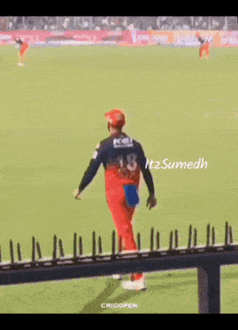 a cricket player jumps over a fence during a game .