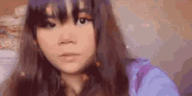 a close up of a woman taking a selfie with a purple shirt on .