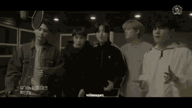 a group of young men are standing next to each other in front of a microphone .
