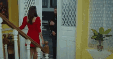 a woman in a red dress walking down stairs