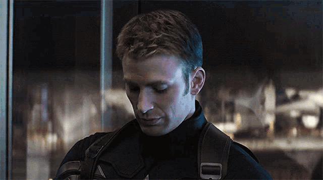 a close up of a man wearing a black jacket with a brown strap