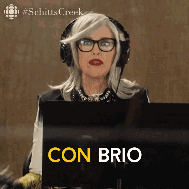 a woman wearing headphones is sitting in front of a computer screen that says " con brio "