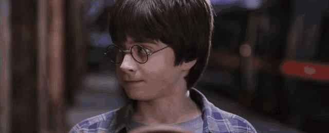 a young boy wearing glasses and a plaid shirt is looking at the camera .