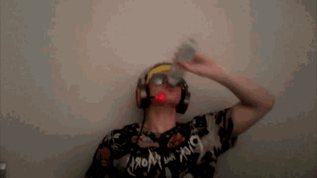 a man wearing headphones and a shirt that says " from the world " drinks from a can