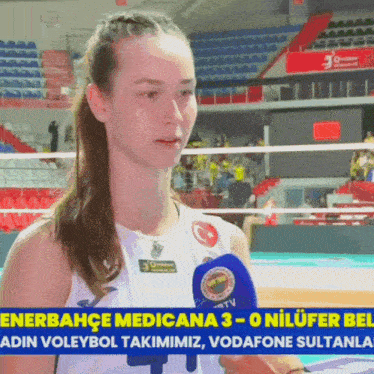 a woman with a microphone in front of a volleyball net