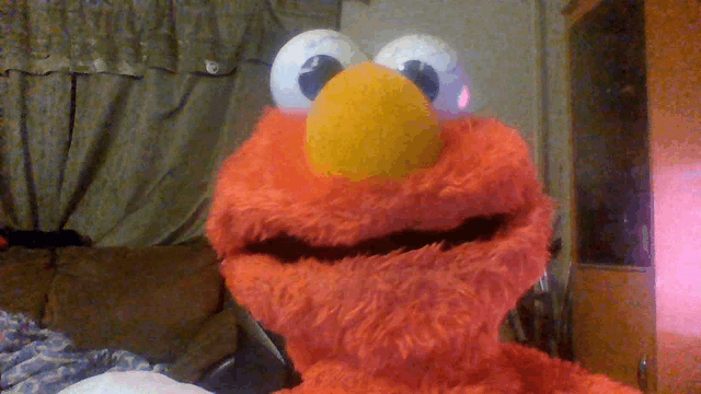 elmo from sesame street is sitting on a couch in a living room