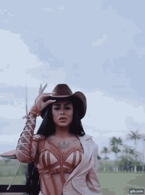a woman wearing a cowboy hat is standing in a field