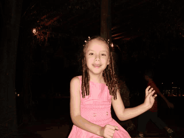 a little girl in a pink dress smiles for the camera at night