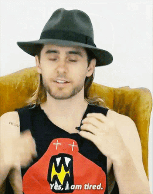 a man wearing a hat and a shirt that says i am tired