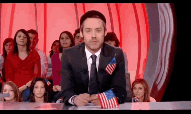 a man in a suit and tie is holding an american flag in his pocket