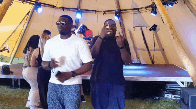 two men are dancing in front of a tent with a sign on it that says ' a ' on it