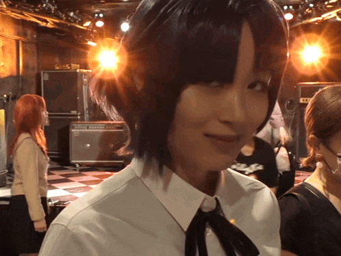 a woman in a white shirt with a black tie stands in front of a fender amp