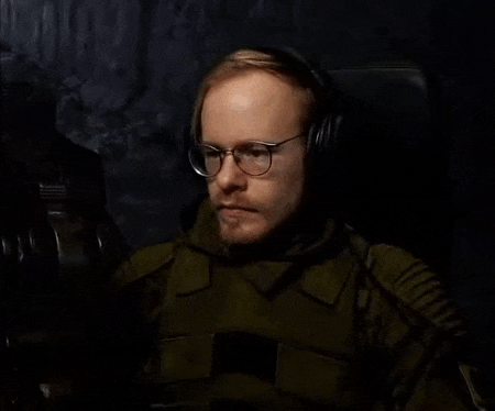 a man wearing glasses and headphones is sitting in a dark room and says `` get lost , bro . ''