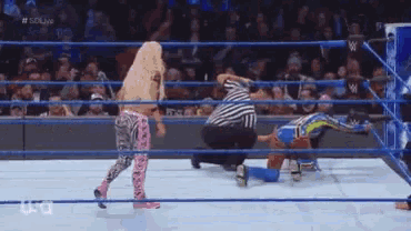 two women are wrestling in a wrestling ring while a referee watches .