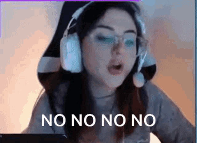 a woman wearing headphones and glasses is sitting in front of a computer and says no no no no .