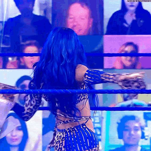 a woman with blue hair is in a wrestling ring .