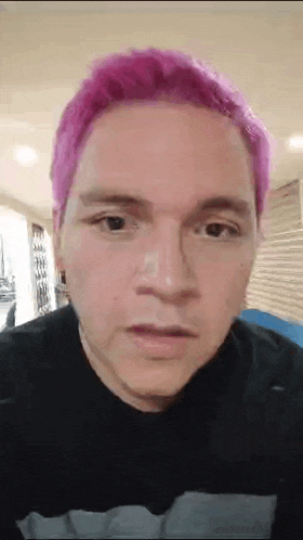 a man with pink hair is wearing a black shirt .