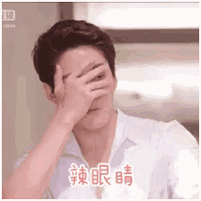 a man in a white shirt is covering his face with his hand in chinese writing .