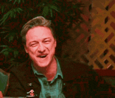 a man is sitting at a table with his eyes closed and laughing