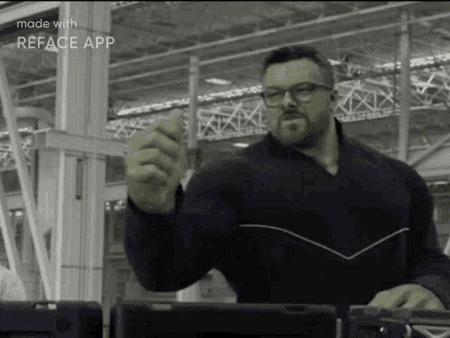 a man wearing glasses and a black shirt is giving a thumbs up