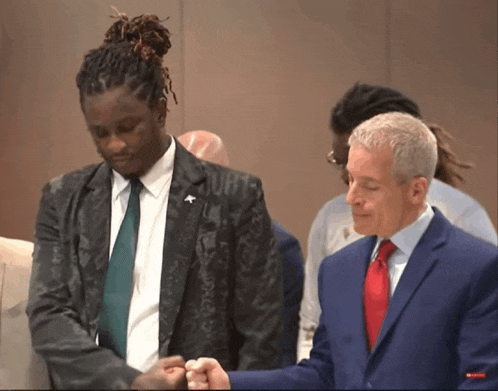 a man in a suit and tie stands next to another man in a suit