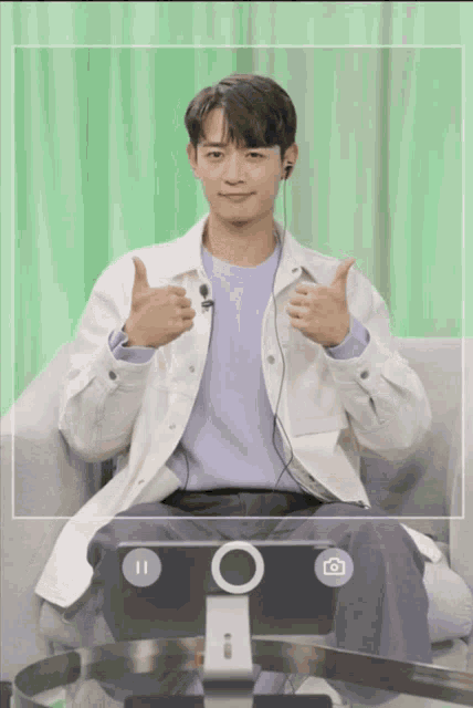 a man is giving a thumbs up in front of a green background