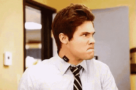 a man in a blue shirt and tie is making a face .