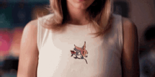 a close up of a woman 's chest with a butterfly embroidered on it .