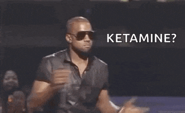 a man wearing sunglasses and a leather shirt is holding a microphone and saying `` ketamine ? ''