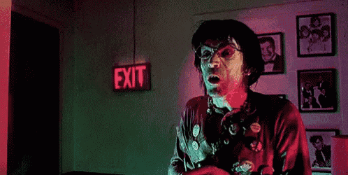 a clown is screaming in front of an exit sign
