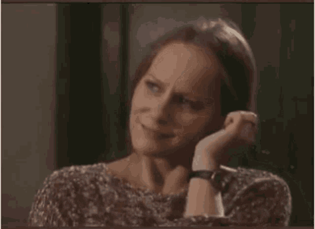 a woman in a floral shirt is holding her hair in a ponytail .