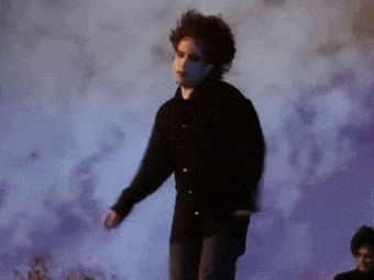 a man in a black shirt stands in front of a purple background