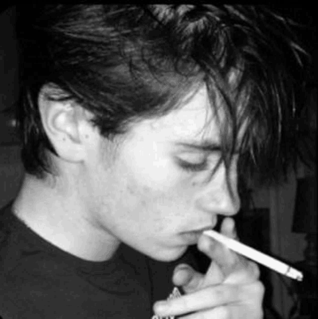 a young man smoking a cigarette in a black and white photo