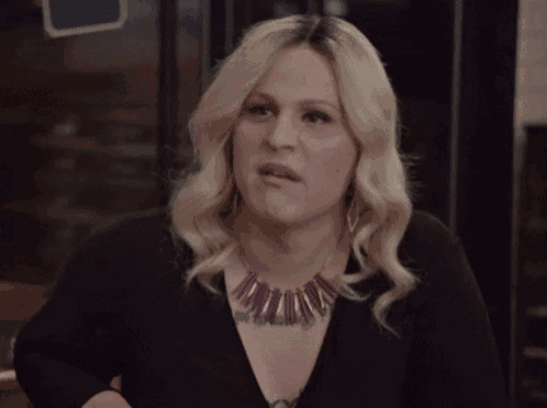 a woman wearing a purple necklace is making a face