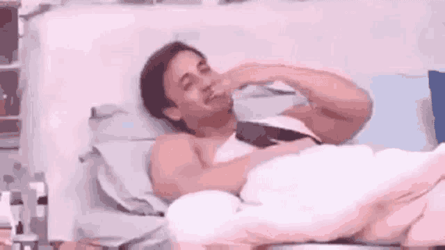 a shirtless man is laying in a bed with a blanket on his head .