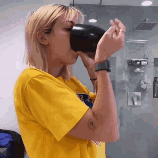 a woman in a yellow shirt is drinking from a large cup