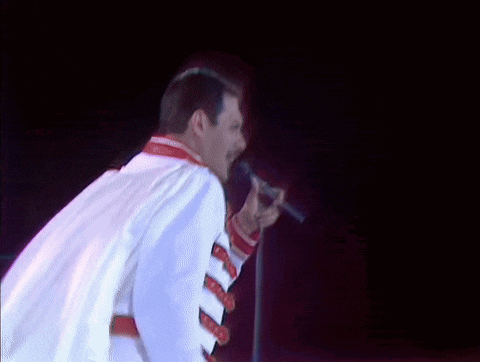 a man in a white jacket is singing into a microphone on a stage